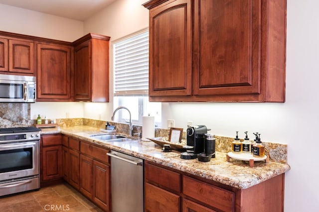 kitchen with light stone counters, stainless steel appliances, and sink