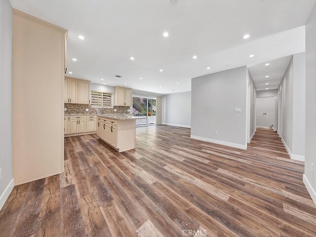 kitchen featuring light stone counters, hardwood / wood-style flooring, sink, decorative backsplash, and cream cabinets