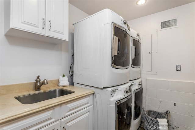 washroom with stacked washing maching and dryer, sink, and cabinets