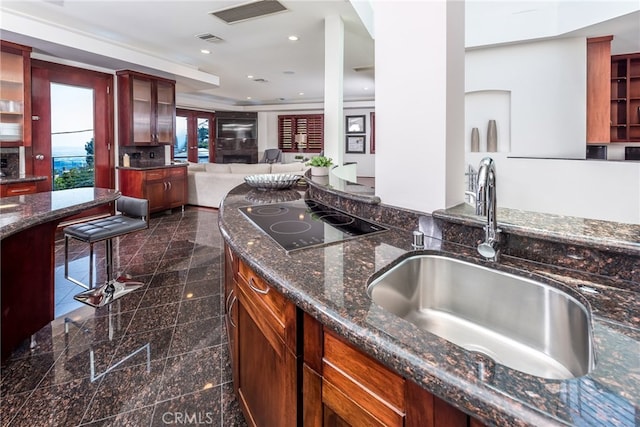 kitchen featuring dark stone countertops, sink, and black electric stovetop