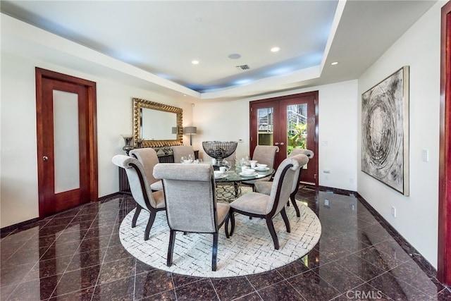 dining area with a tray ceiling and french doors