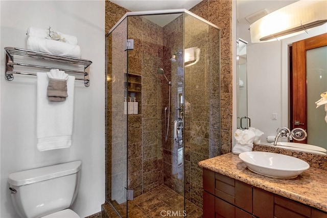 bathroom featuring vanity, a shower with shower door, and toilet