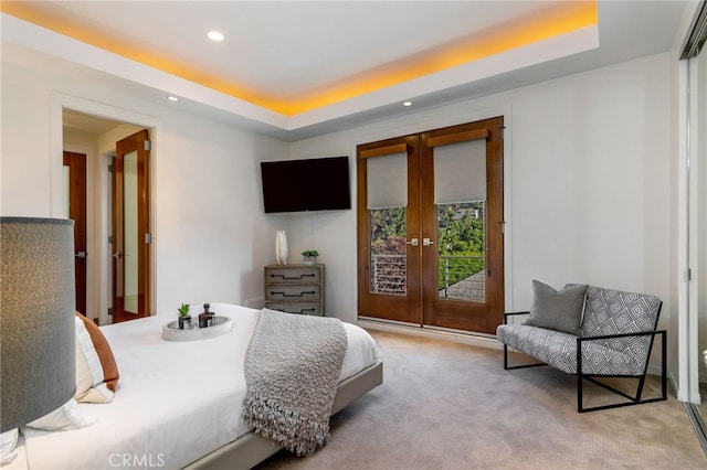 carpeted bedroom featuring access to outside, a raised ceiling, and french doors