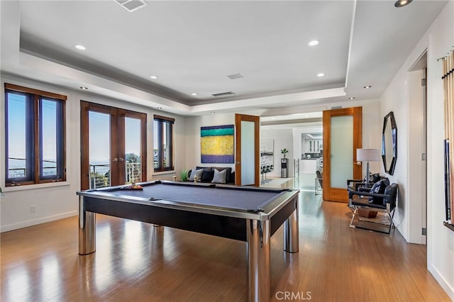 recreation room with pool table, light hardwood / wood-style flooring, a tray ceiling, and french doors