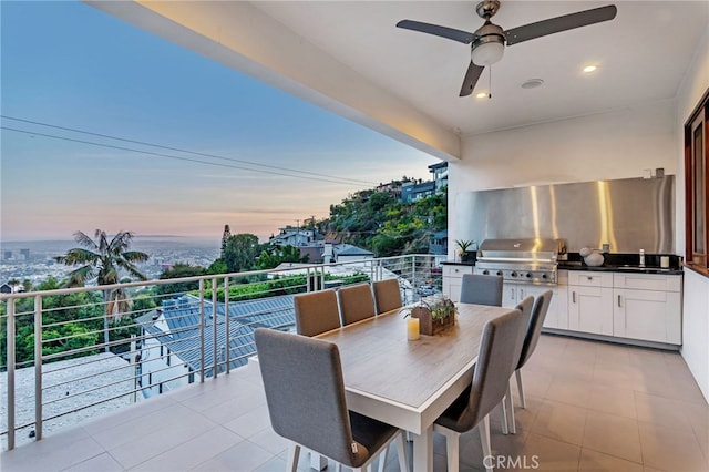 patio terrace at dusk with area for grilling, a balcony, and sink