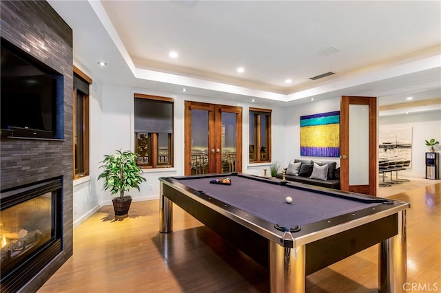 playroom featuring a large fireplace, light hardwood / wood-style flooring, billiards, and a tray ceiling