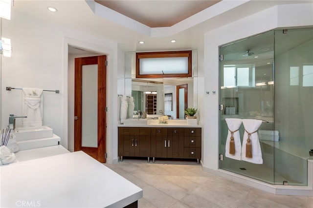 bathroom with a raised ceiling, tile patterned flooring, vanity, and a shower with shower door