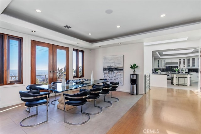 tiled dining space featuring a tray ceiling and french doors