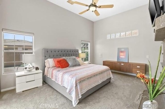 bedroom with ceiling fan, a towering ceiling, and light carpet