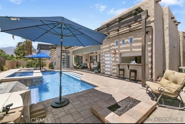 view of swimming pool with a bar, a patio, and an in ground hot tub