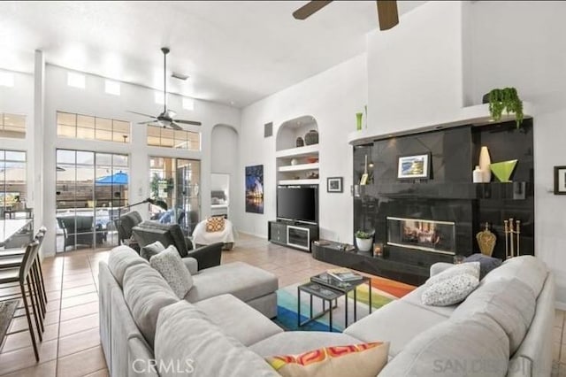 living room featuring built in features, ceiling fan, and light tile patterned flooring