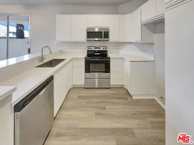 kitchen with stainless steel appliances, white cabinetry, light hardwood / wood-style floors, and sink