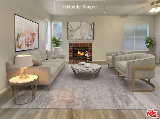 living room featuring wood-type flooring, a fireplace, and ceiling fan