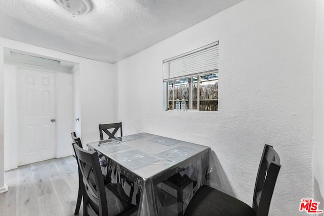 dining area with light wood-type flooring and a textured ceiling