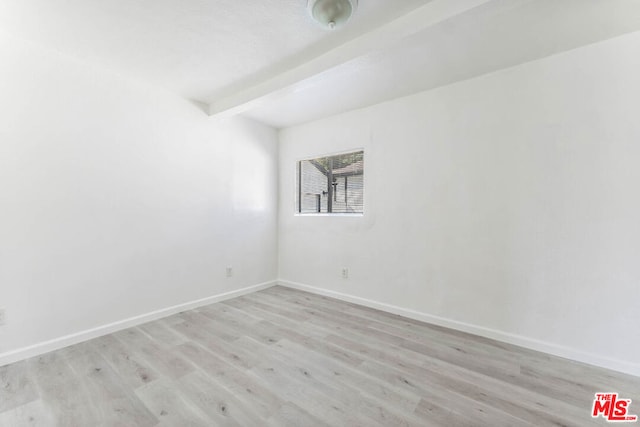 spare room featuring light hardwood / wood-style flooring and beamed ceiling