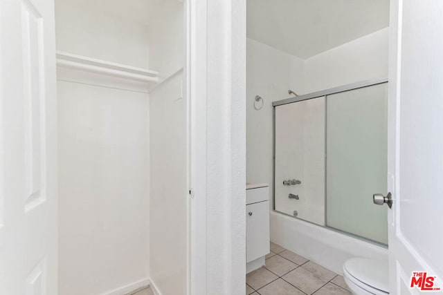 bathroom featuring tile patterned flooring, shower / bath combination with glass door, and toilet