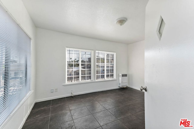 spare room featuring heating unit and dark tile patterned floors