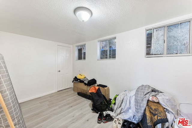 misc room with light wood-type flooring and a textured ceiling