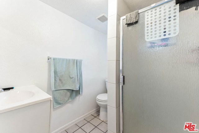 bathroom featuring vanity, toilet, tile patterned floors, and a shower with shower door