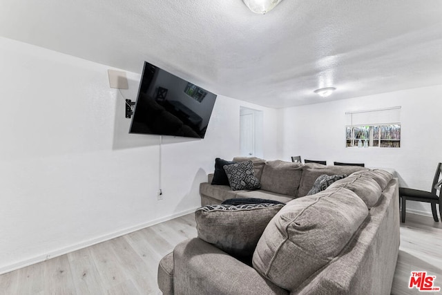 living room featuring light wood-type flooring and a textured ceiling