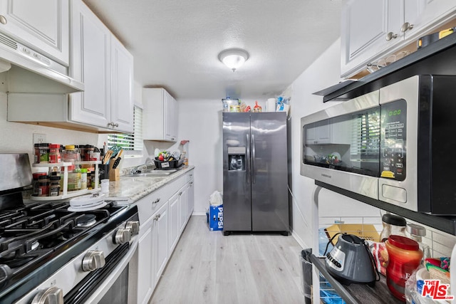 kitchen featuring light hardwood / wood-style floors, white cabinets, stainless steel appliances, range hood, and sink