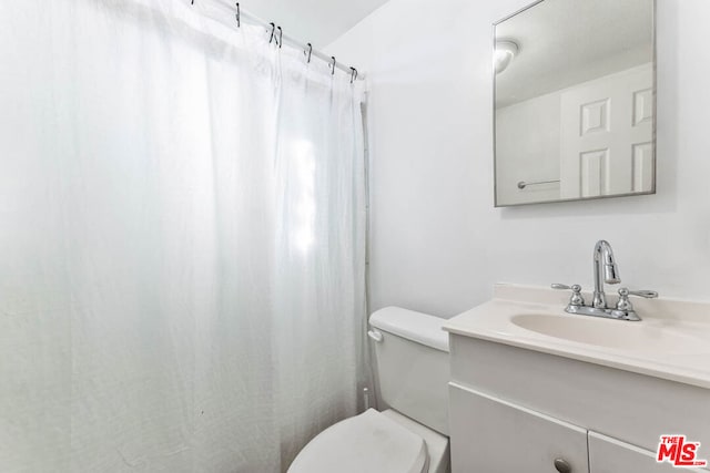 bathroom featuring a shower with curtain, vanity, and toilet