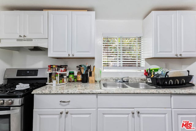 kitchen with stainless steel gas range oven, sink, and white cabinets