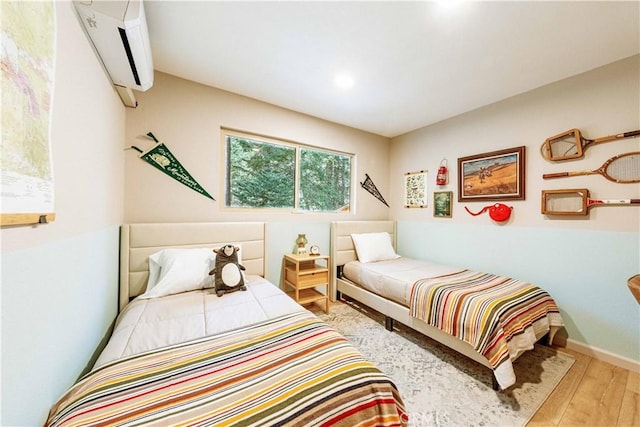 bedroom with a wall mounted AC and light hardwood / wood-style floors