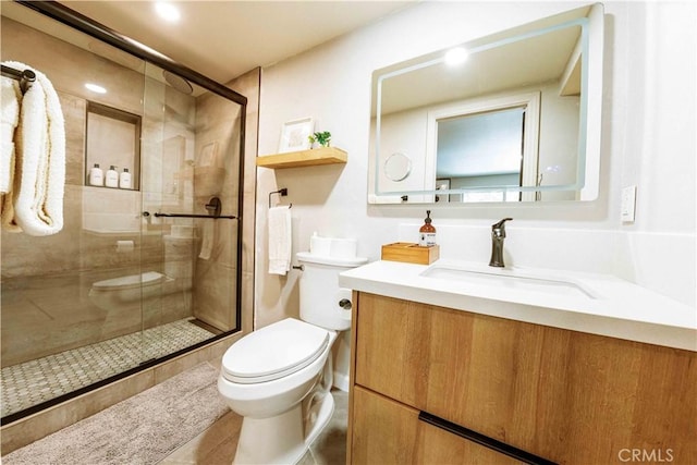 bathroom featuring a shower with door, vanity, and toilet