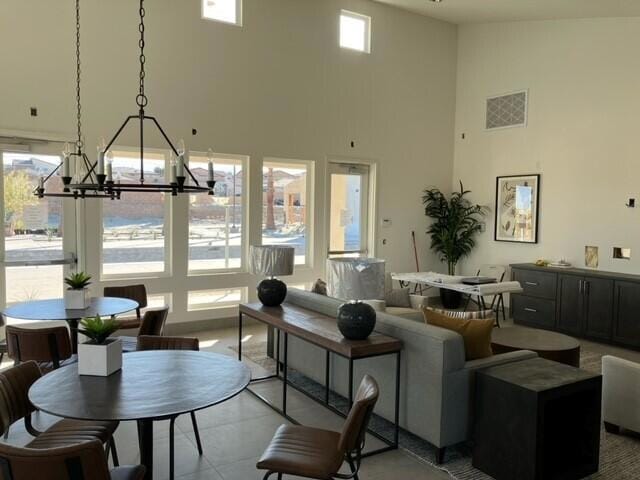 living room with a wealth of natural light, a towering ceiling, and a notable chandelier