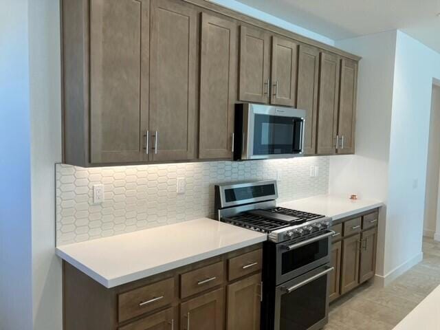 kitchen featuring appliances with stainless steel finishes, light tile patterned flooring, and tasteful backsplash