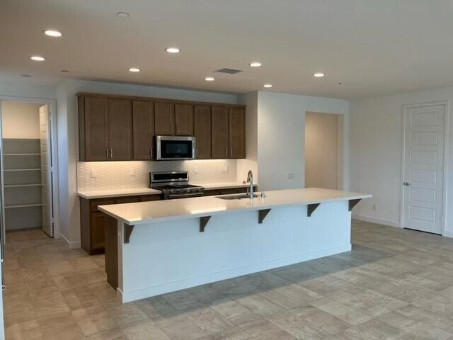 kitchen featuring a center island with sink, stainless steel appliances, sink, and decorative backsplash