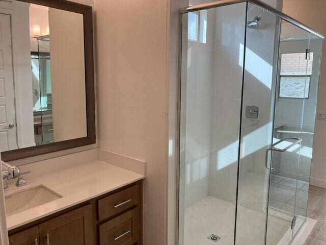 bathroom with walk in shower, tile patterned flooring, and vanity