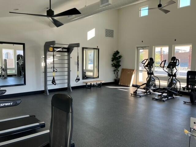 exercise room featuring a towering ceiling, ceiling fan, and plenty of natural light