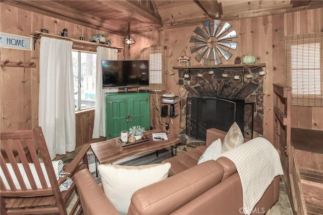 living room with a fireplace, beam ceiling, wooden walls, and wooden ceiling