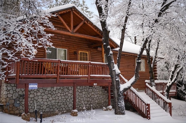 snow covered rear of property with stairway