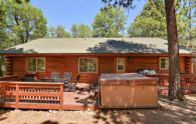 back of house with a deck, an outdoor living space, and a hot tub