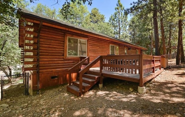 rear view of house with log exterior, a wooden deck, and fence