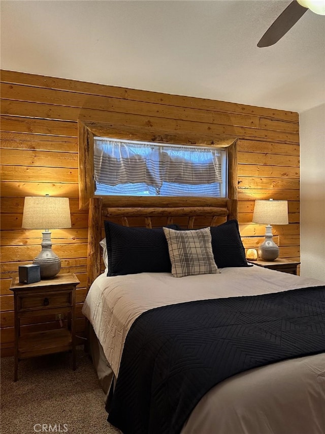 carpeted bedroom with ceiling fan and wood walls