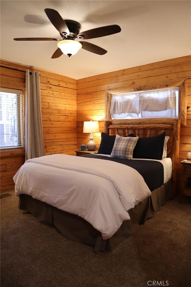 carpeted bedroom with wooden walls and ceiling fan