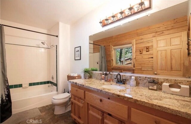 full bathroom with vanity, wooden walls, toilet, and shower / tub combo with curtain