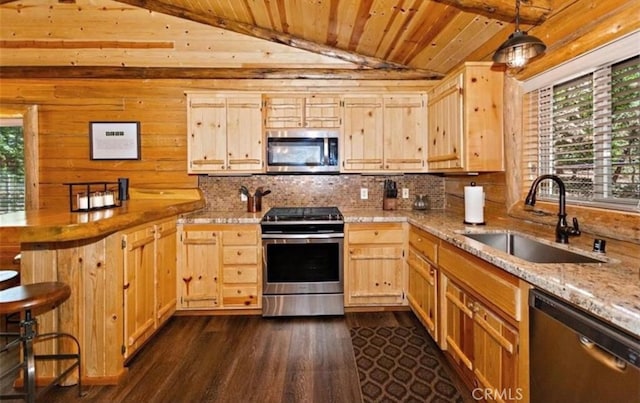 kitchen featuring decorative light fixtures, stainless steel appliances, wood walls, and light brown cabinets