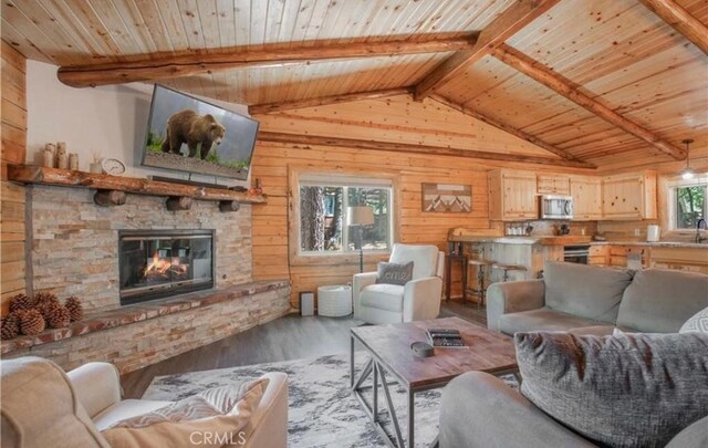 living room with a stone fireplace, plenty of natural light, light hardwood / wood-style floors, and wooden ceiling