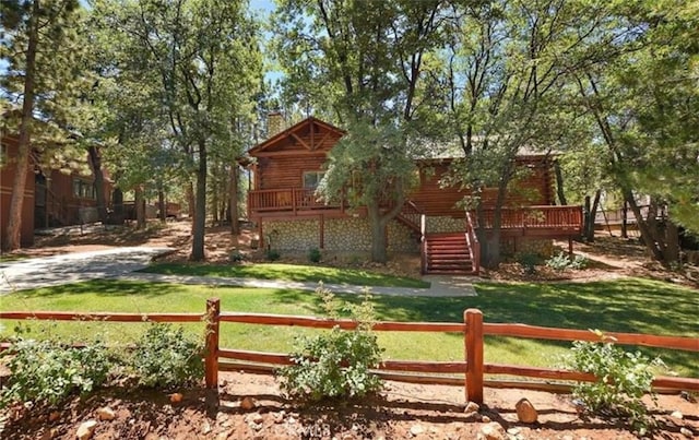 view of yard featuring a deck, stairway, and a fenced front yard