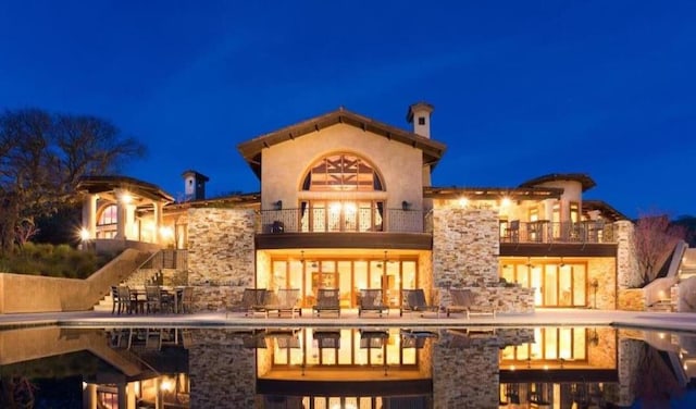 back house at night featuring a balcony