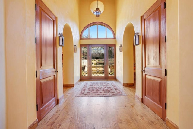 doorway with a towering ceiling and light wood-type flooring