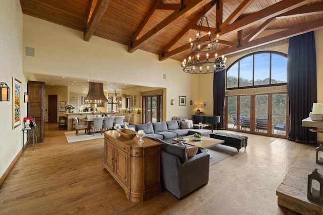 living room with beam ceiling, high vaulted ceiling, a notable chandelier, light hardwood / wood-style floors, and wooden ceiling