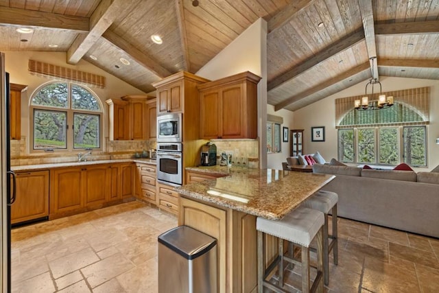 kitchen with appliances with stainless steel finishes, backsplash, a notable chandelier, light stone countertops, and decorative light fixtures