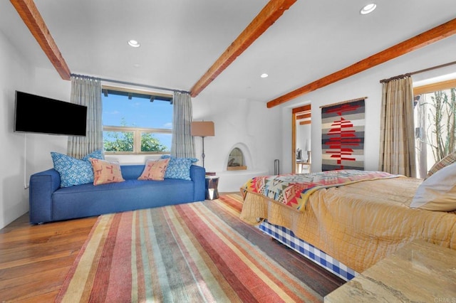 bedroom featuring beam ceiling, multiple windows, and hardwood / wood-style floors