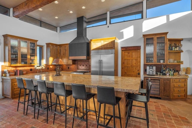 kitchen with a large island, sink, a kitchen breakfast bar, backsplash, and stainless steel built in fridge